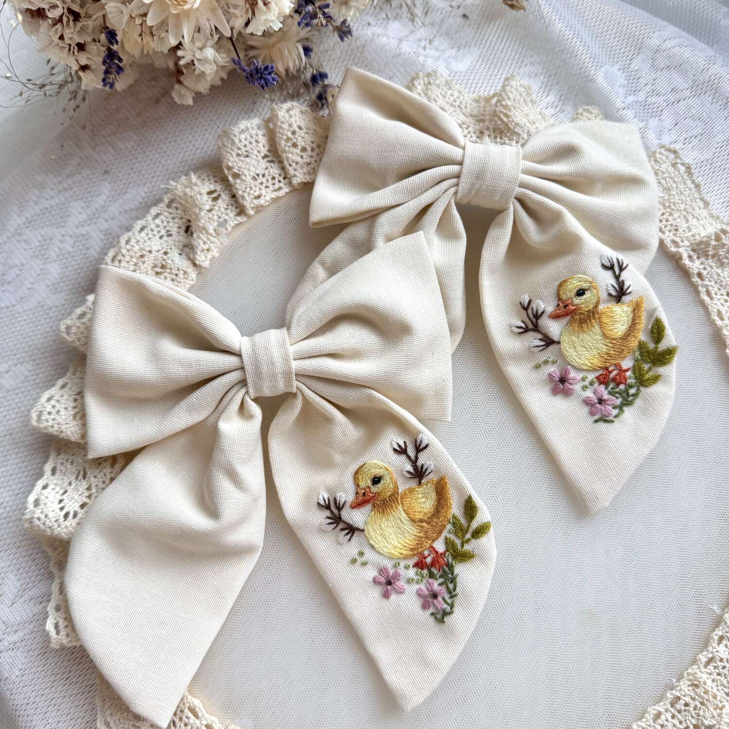 Käsin kirjottu hiusrusetti, ankanpoikanen ja villikukka -aiheinen kuvio kankaalla