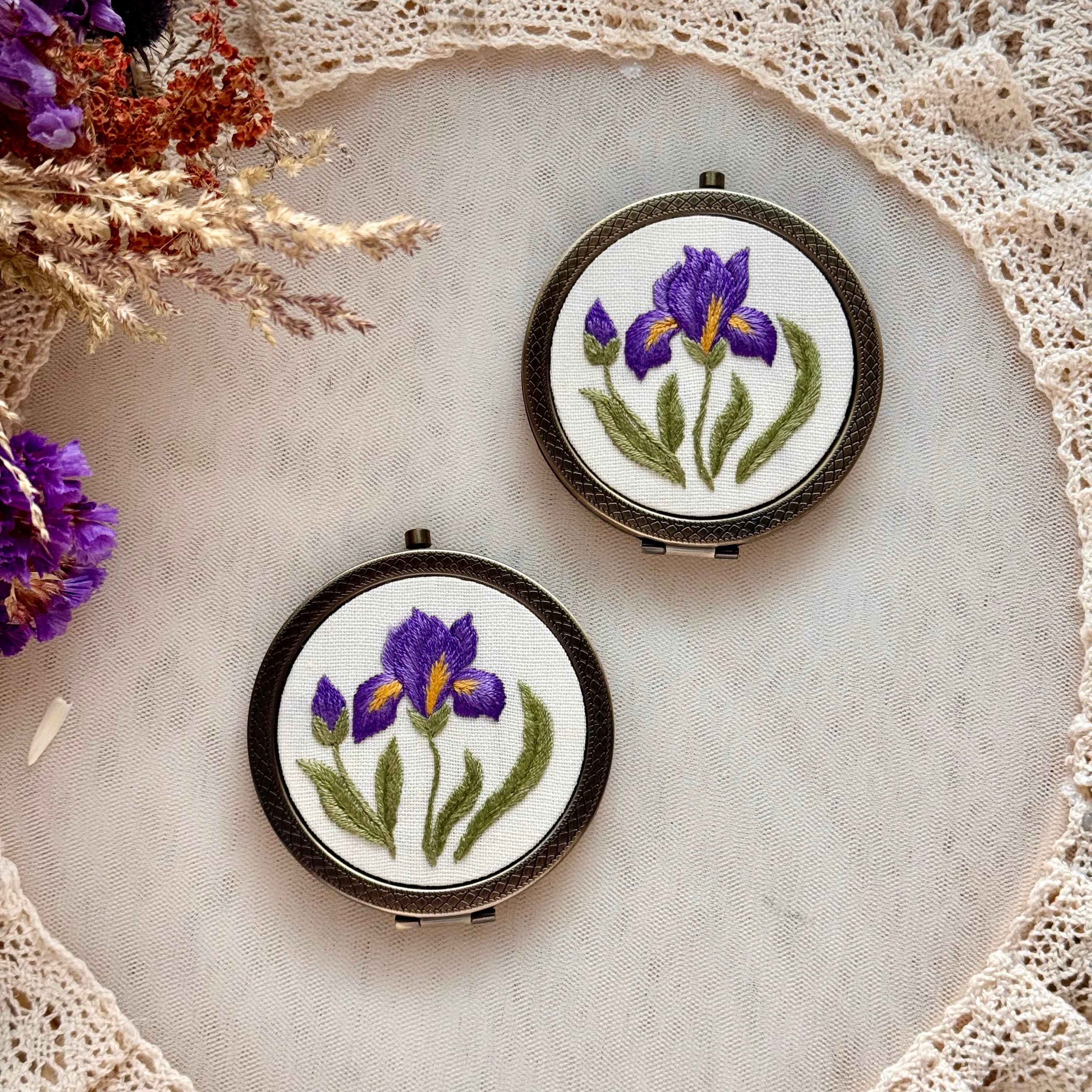 Käsin kirjottu taskupeili, etelänkurjenmiekka-aiheinen kuvio kannessa