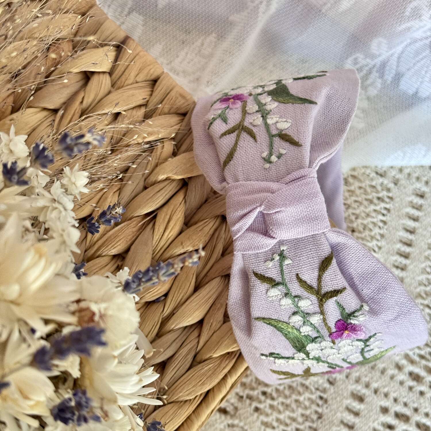 Käsin kirjottu turbaanipanta, kielo ja luhtalemmikki -aiheinen kuvio kankaalla