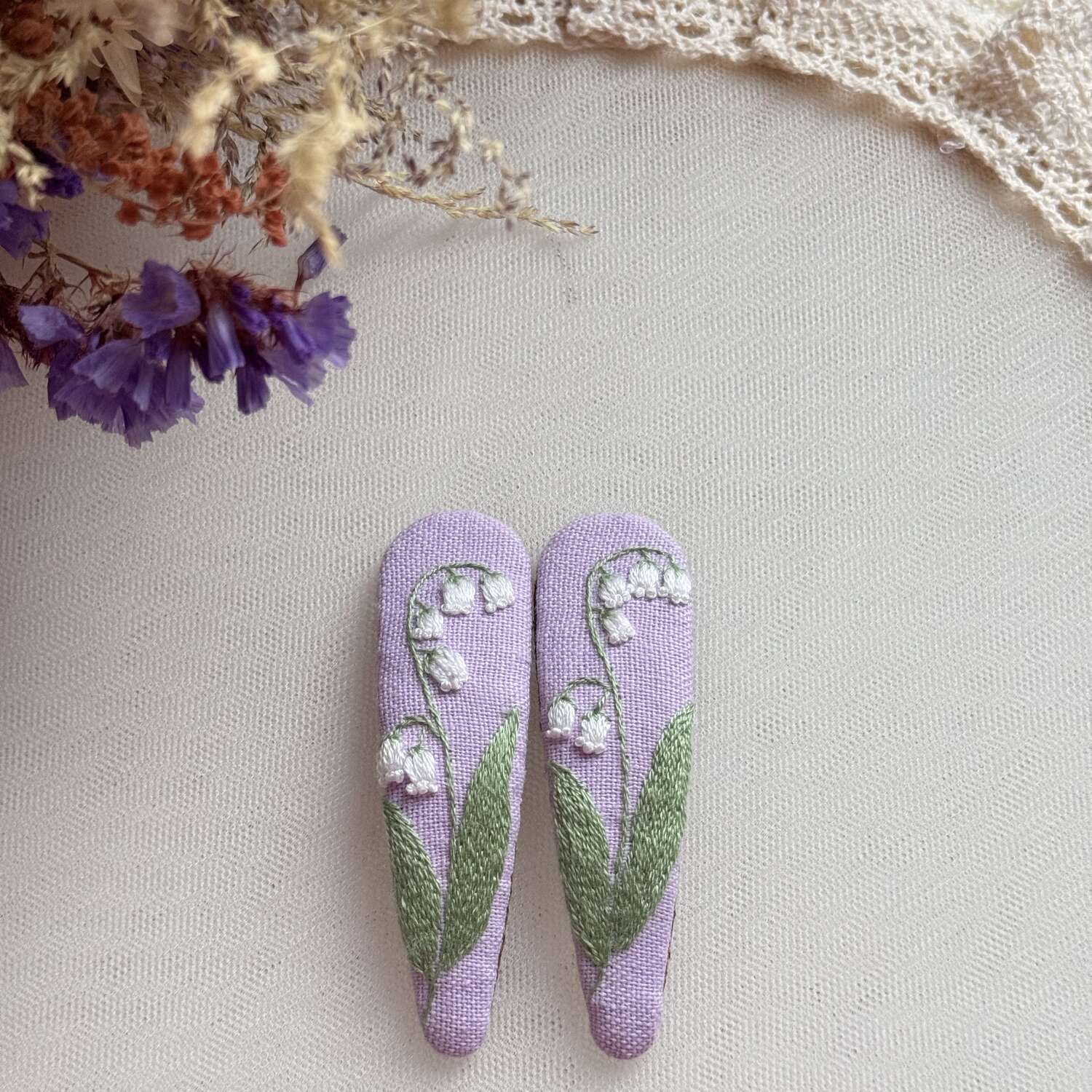 Käsin kirjotut hiuspinnit, kielo-aiheinen kuvio kankaalla