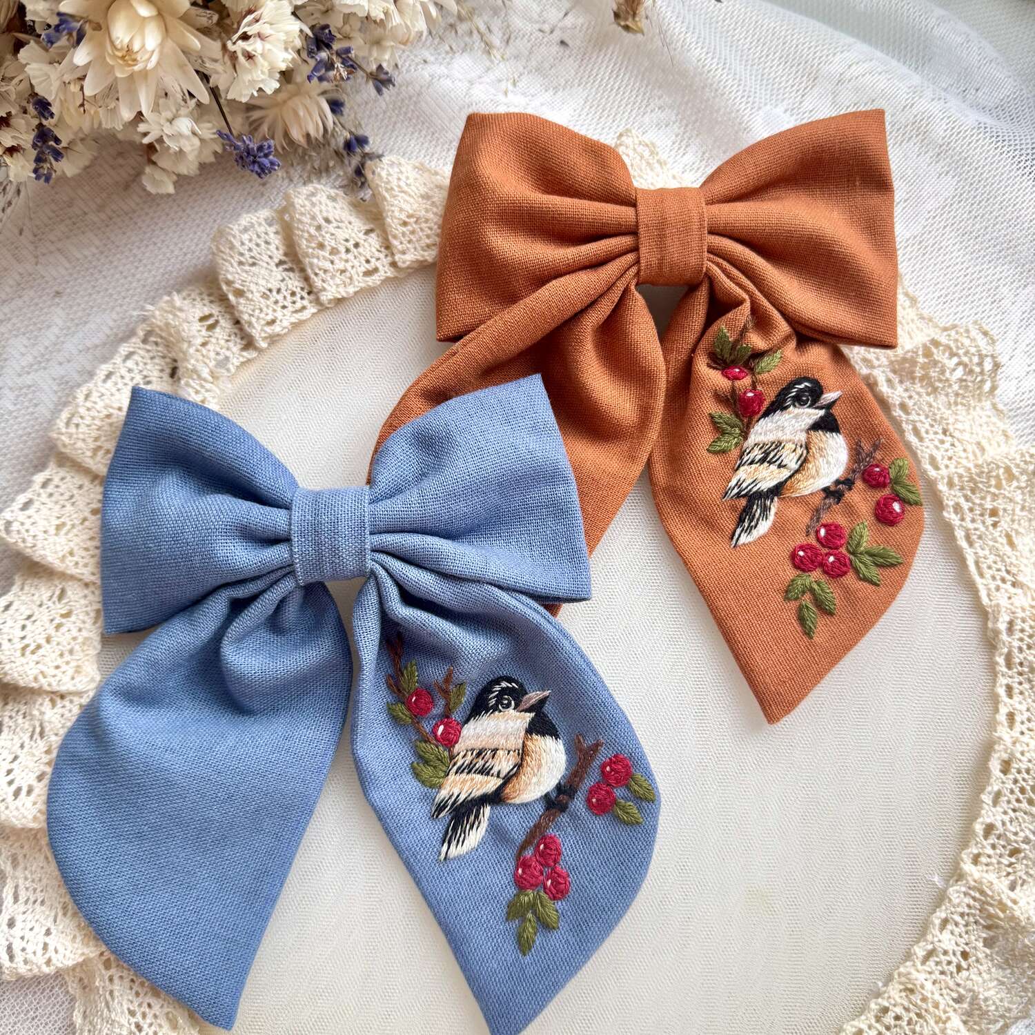 Käsin kirjottu hiusrusetti, kuusitiainen ja pihlaja -aiheinen kuvio kankaalla