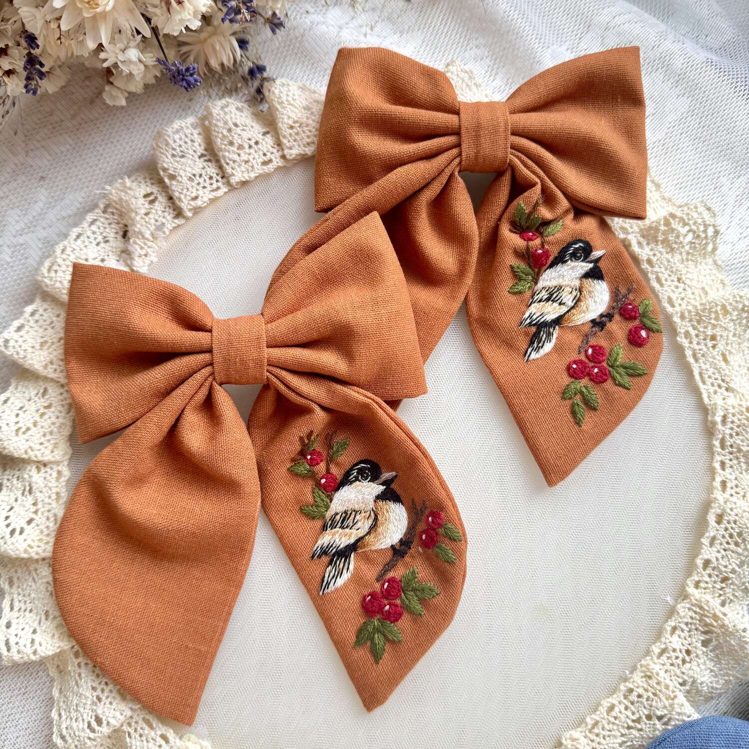 Käsin kirjottu hiusrusetti, kuusitiainen ja pihlaja -aiheinen kuvio kankaalla