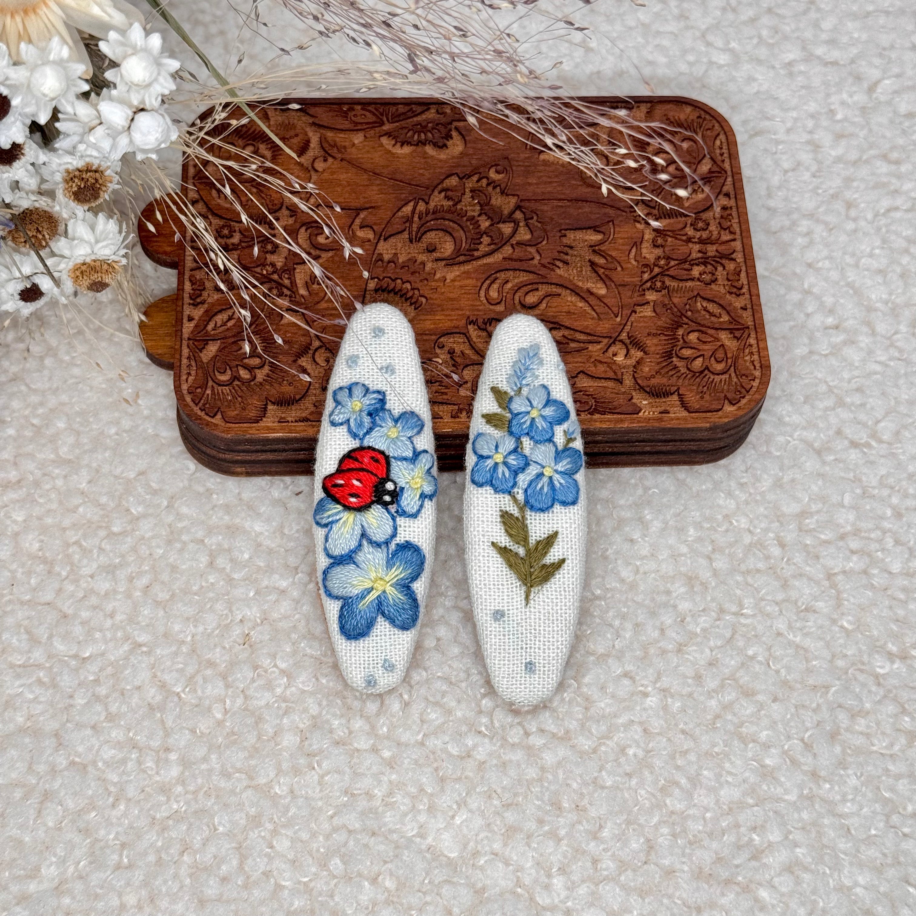 Käsin kirjotut hiuspinnit, lemmikki ja leppäkerttu -aiheinen kuvio kankaalla