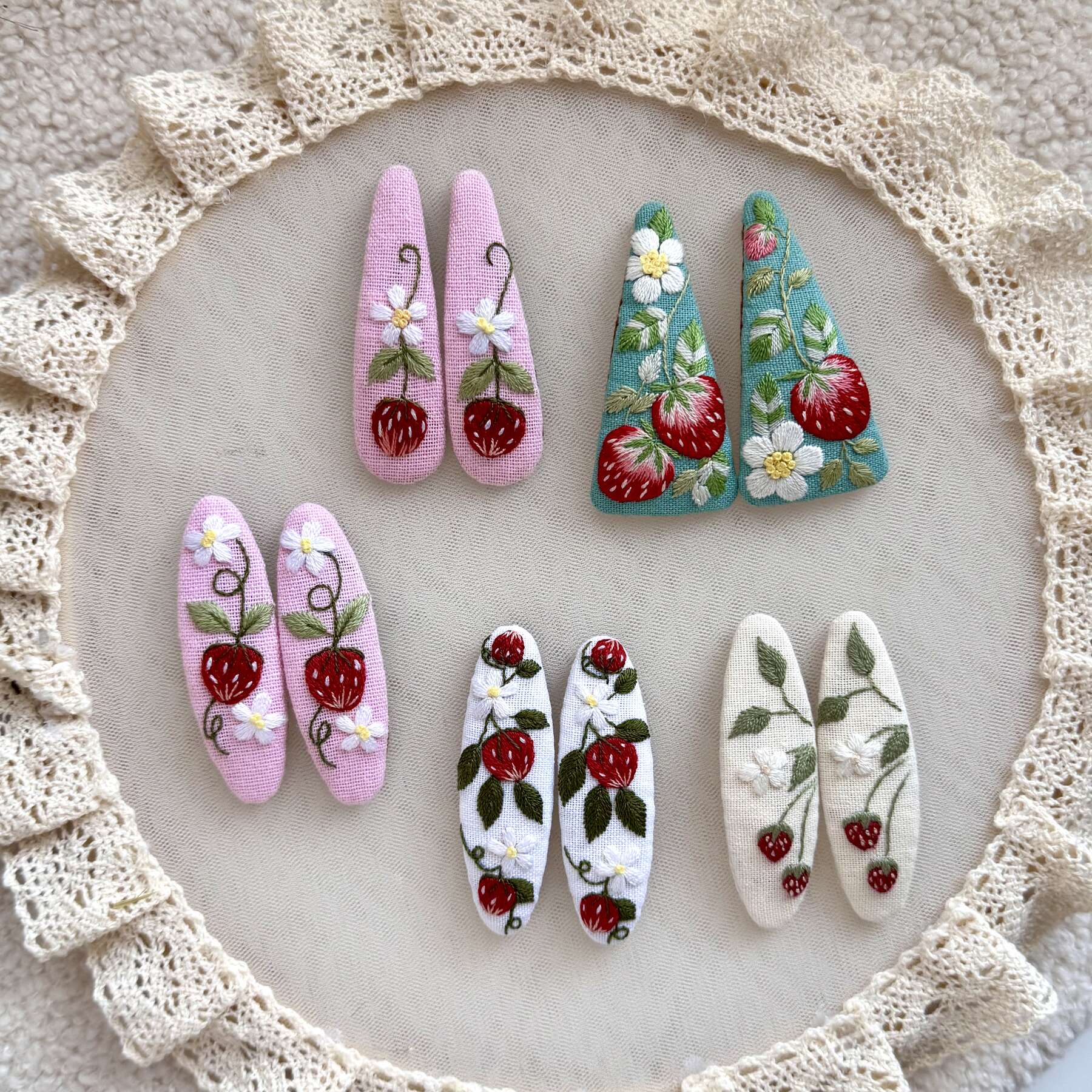 Käsin kirjotut hiuspinnit, metsämansikka ja kukka -aiheinen kuvio kankaalla