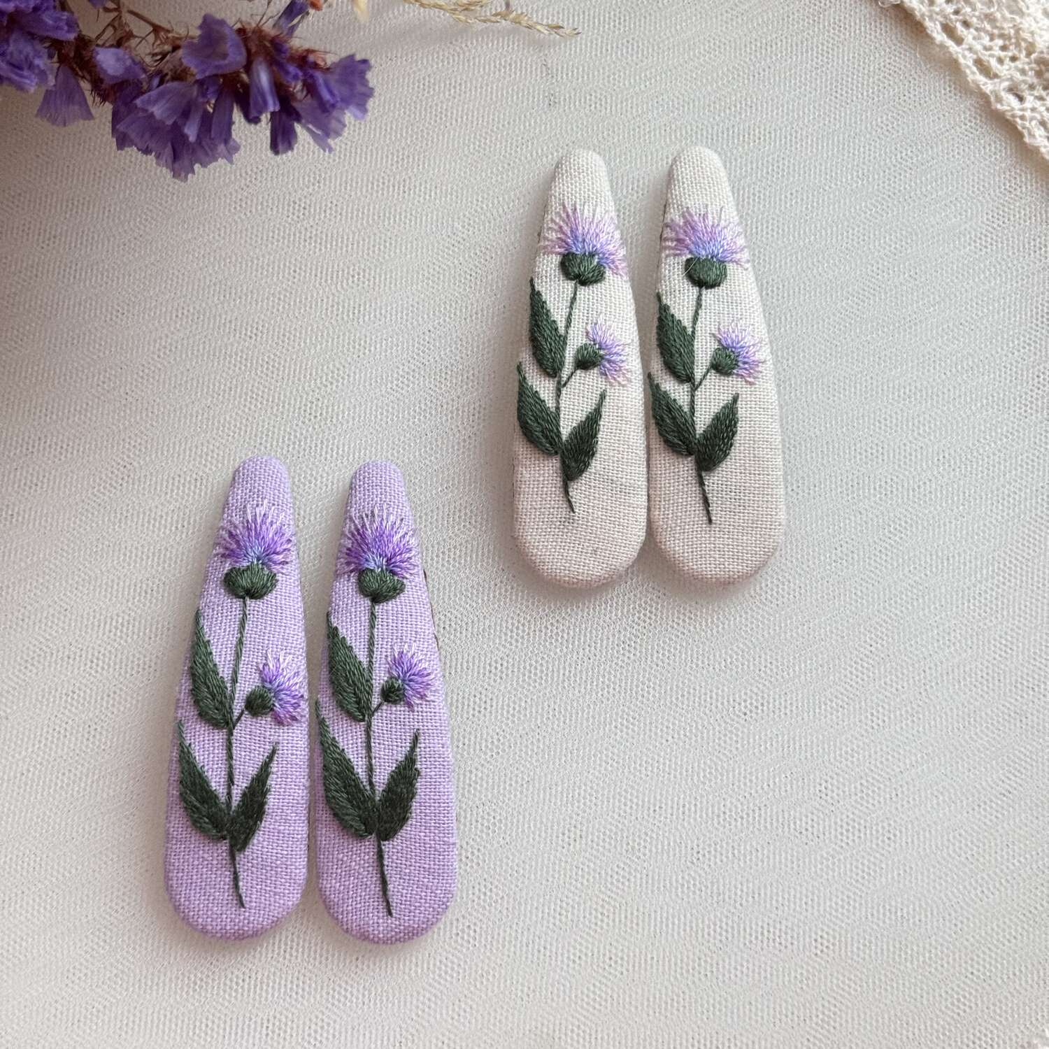 Käsin kirjotut hiuspinnit, niittyohdake-aiheinen kuvio kankaalla