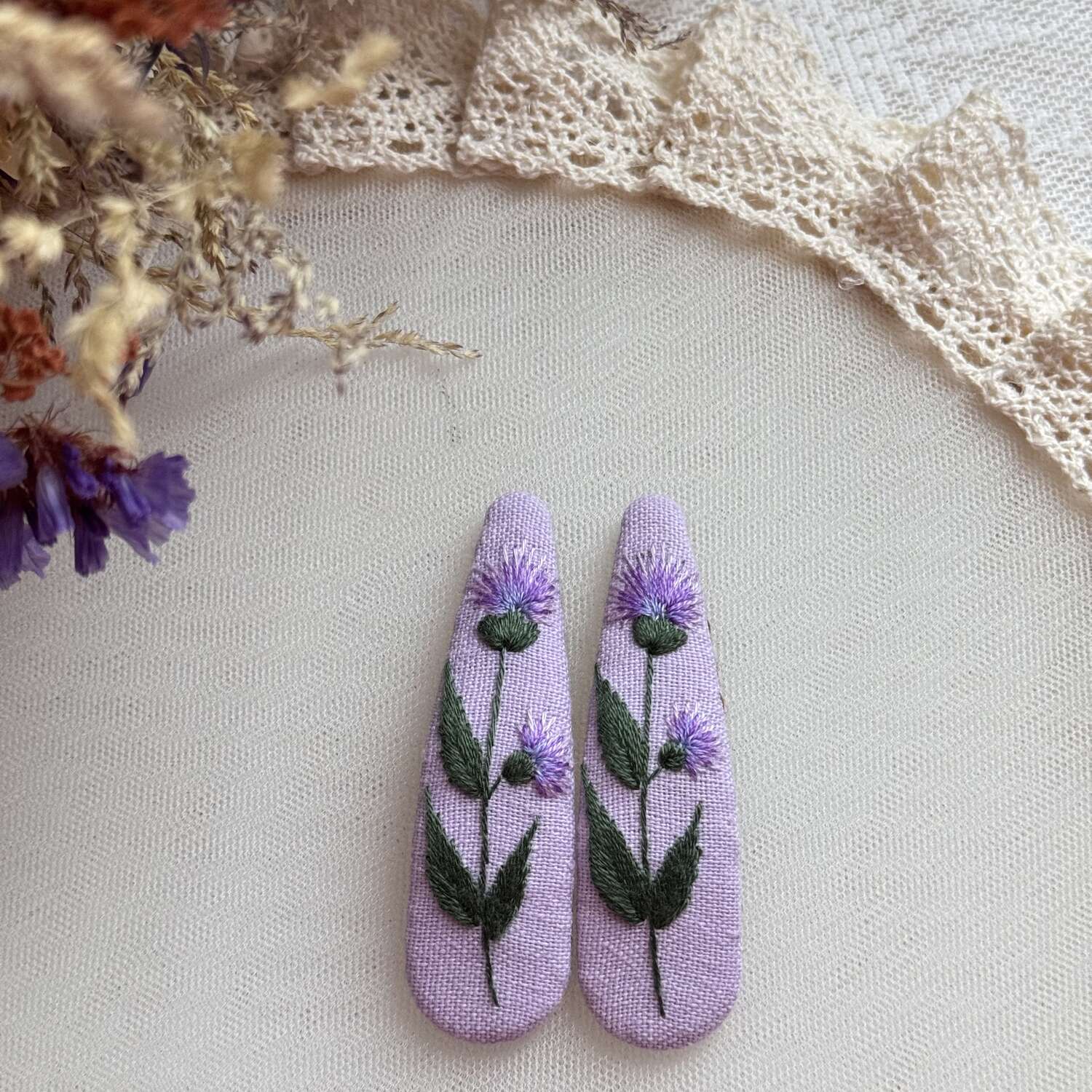 Käsin kirjotut hiuspinnit, niittyohdake-aiheinen kuvio kankaalla