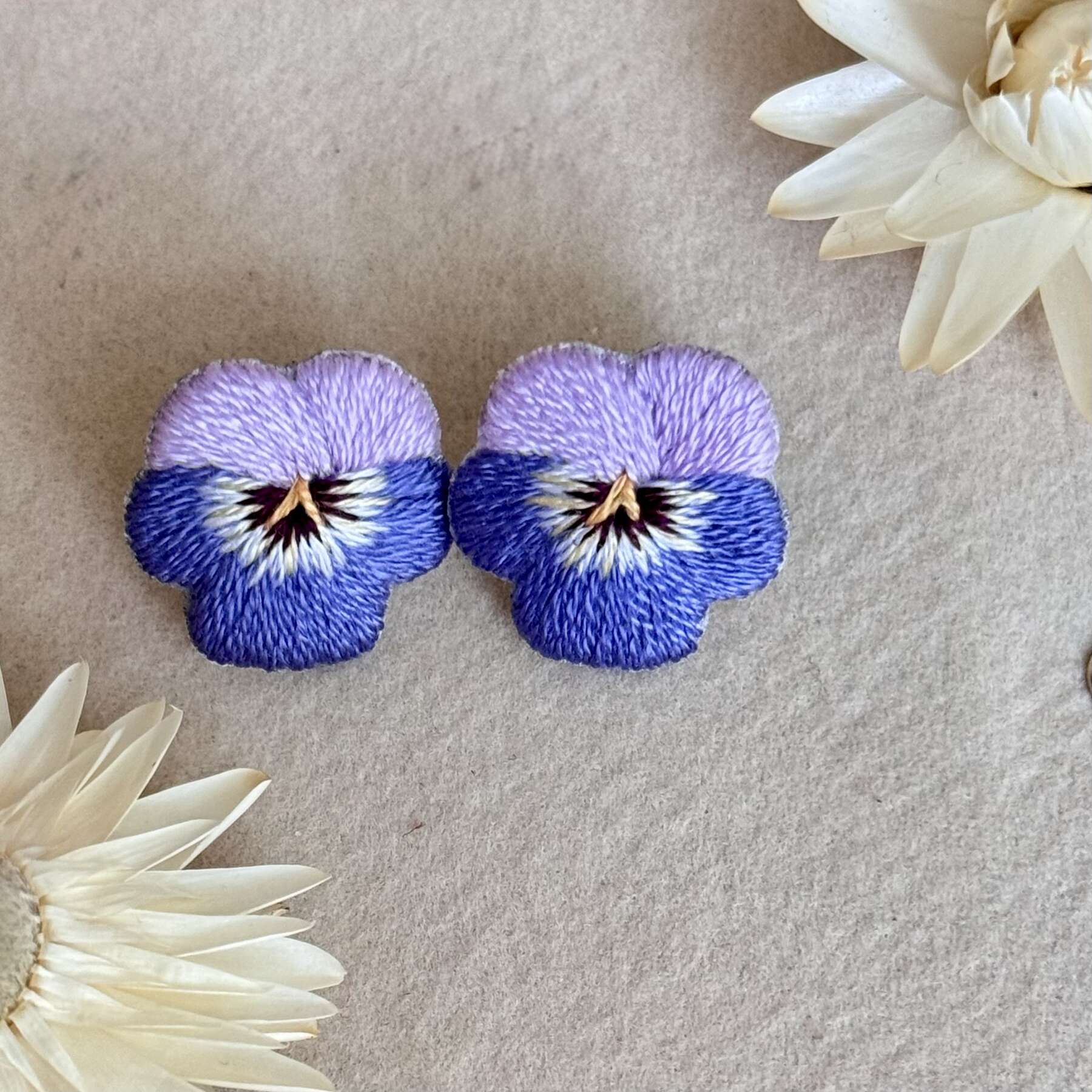 Käsin kirjotut korvakorut, orvokki-aiheinen kuvio