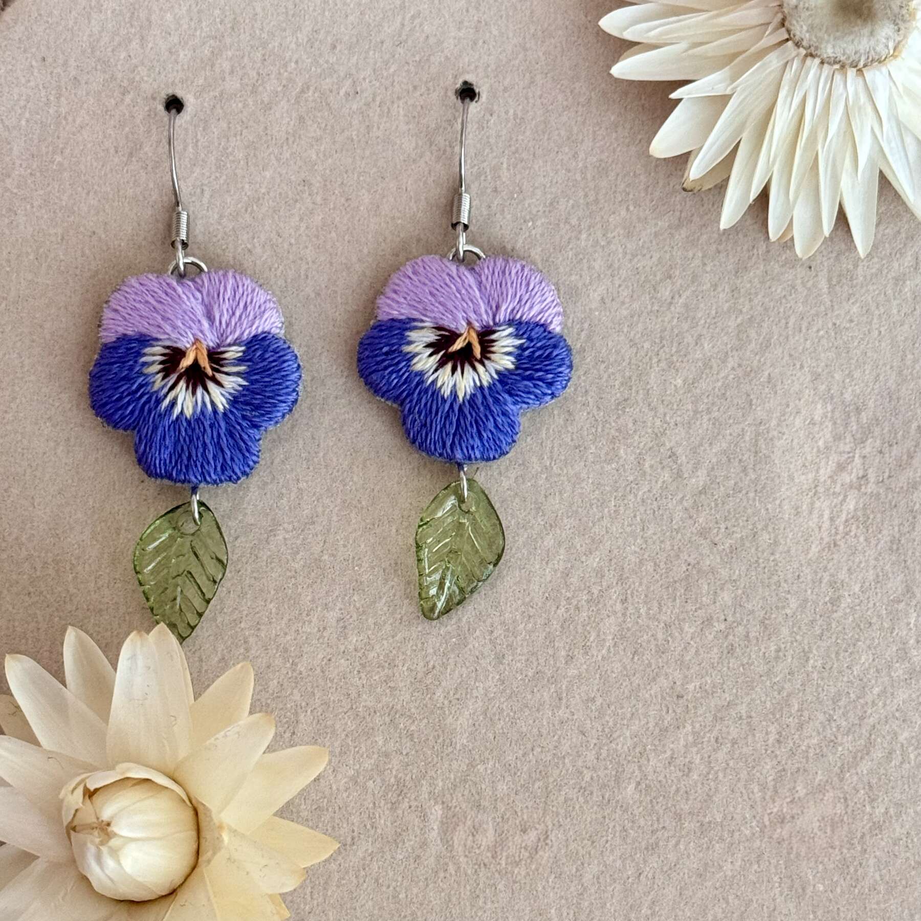 Käsin kirjotut korvakorut, orvokki-aiheinen kuvio