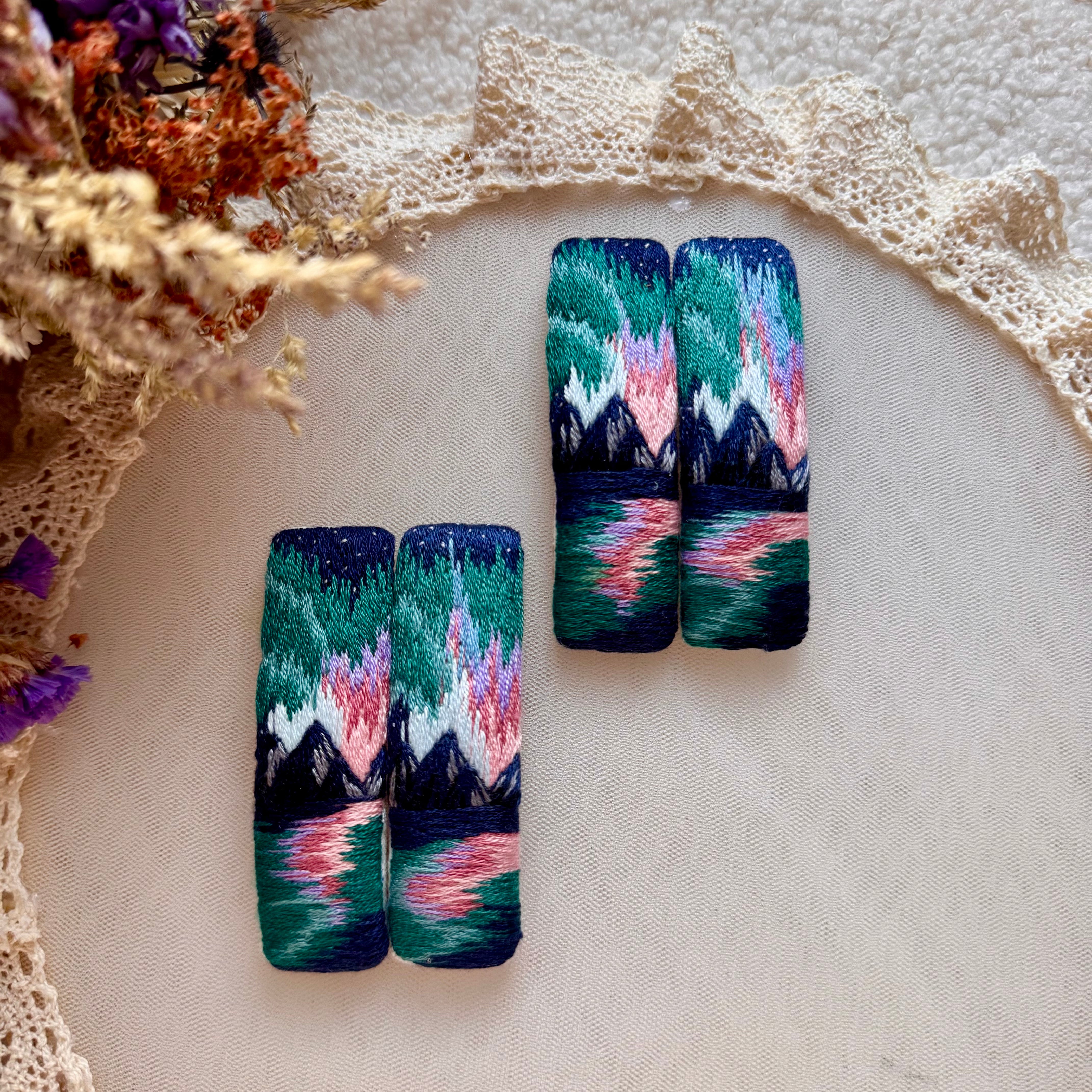 Käsin kirjottu maisemahiuspinni, revontulet-aiheinen kuvio kankaalla