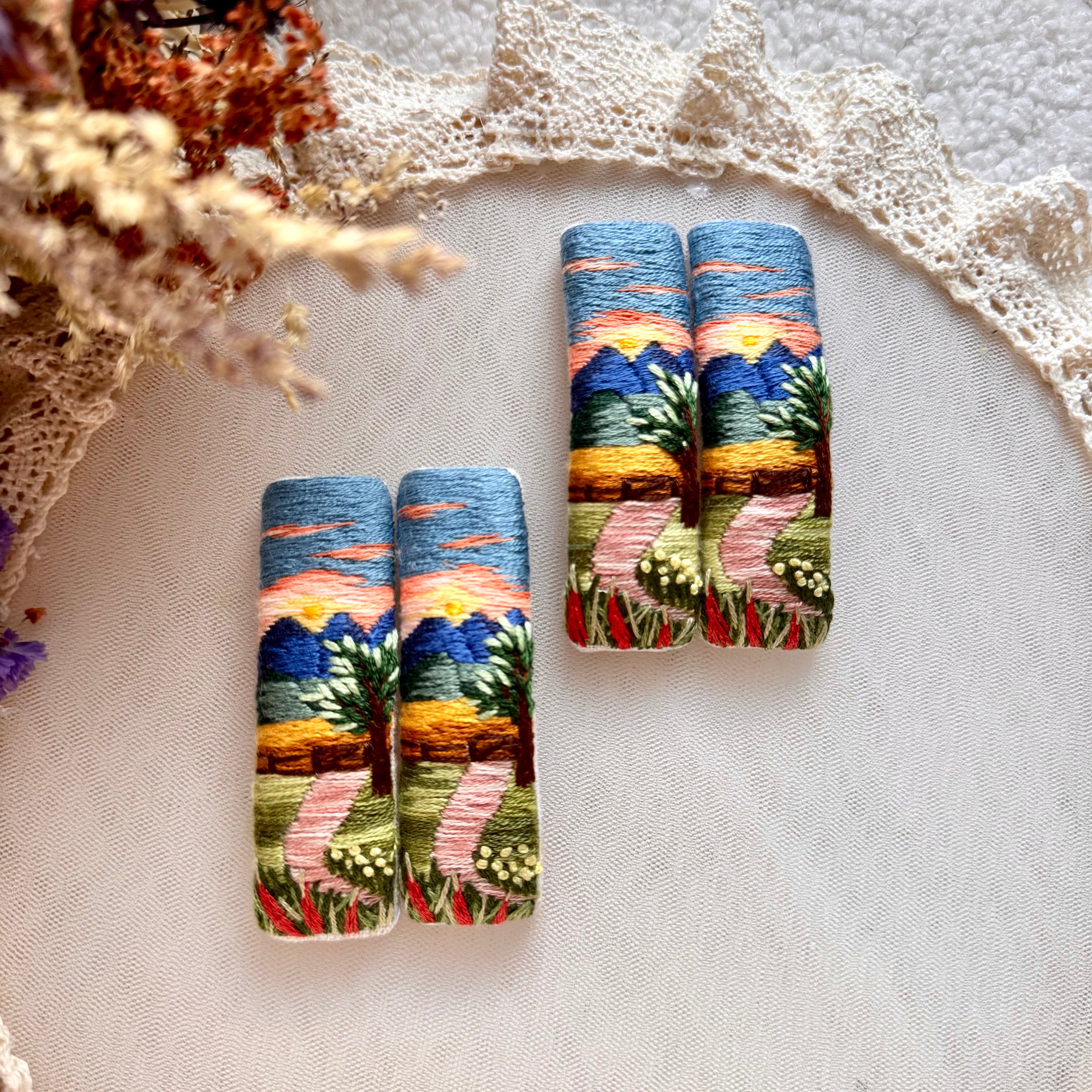 Käsin kirjottu maisemahiuspinni, syksyinen auringonlasku -aiheinen kuvio kankaalla