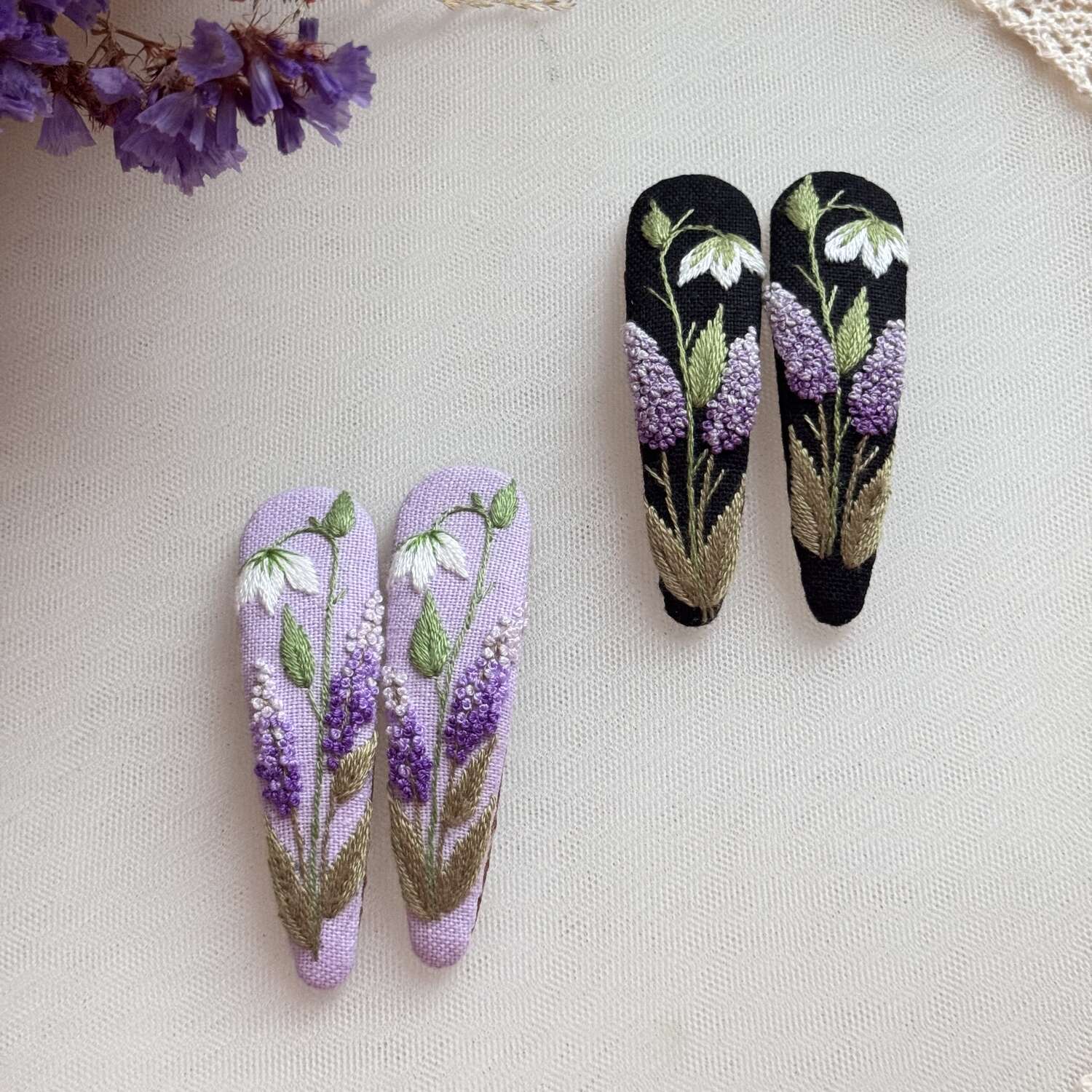 Käsin kirjotut hiuspinnit, vanamo ja syreeni -aiheinen kuvio kankaalla