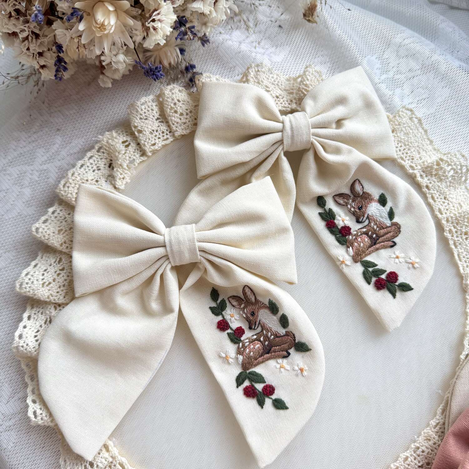 Käsin kirjottu hiusrusetti, vasa kukkapensaassa -aiheinen kuvio kankaalla