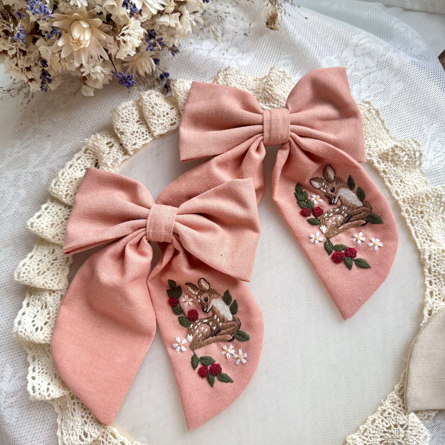 Käsin kirjottu hiusrusetti, vasa kukkapensaassa -aiheinen kuvio kankaalla