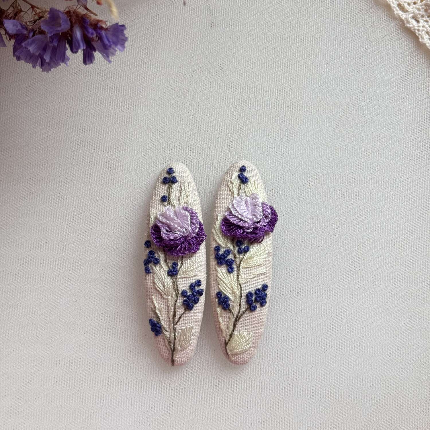 Käsin kirjotut hiuspinnit, violetti ruusu ja mustikka -aiheinen kuvio kankaalla